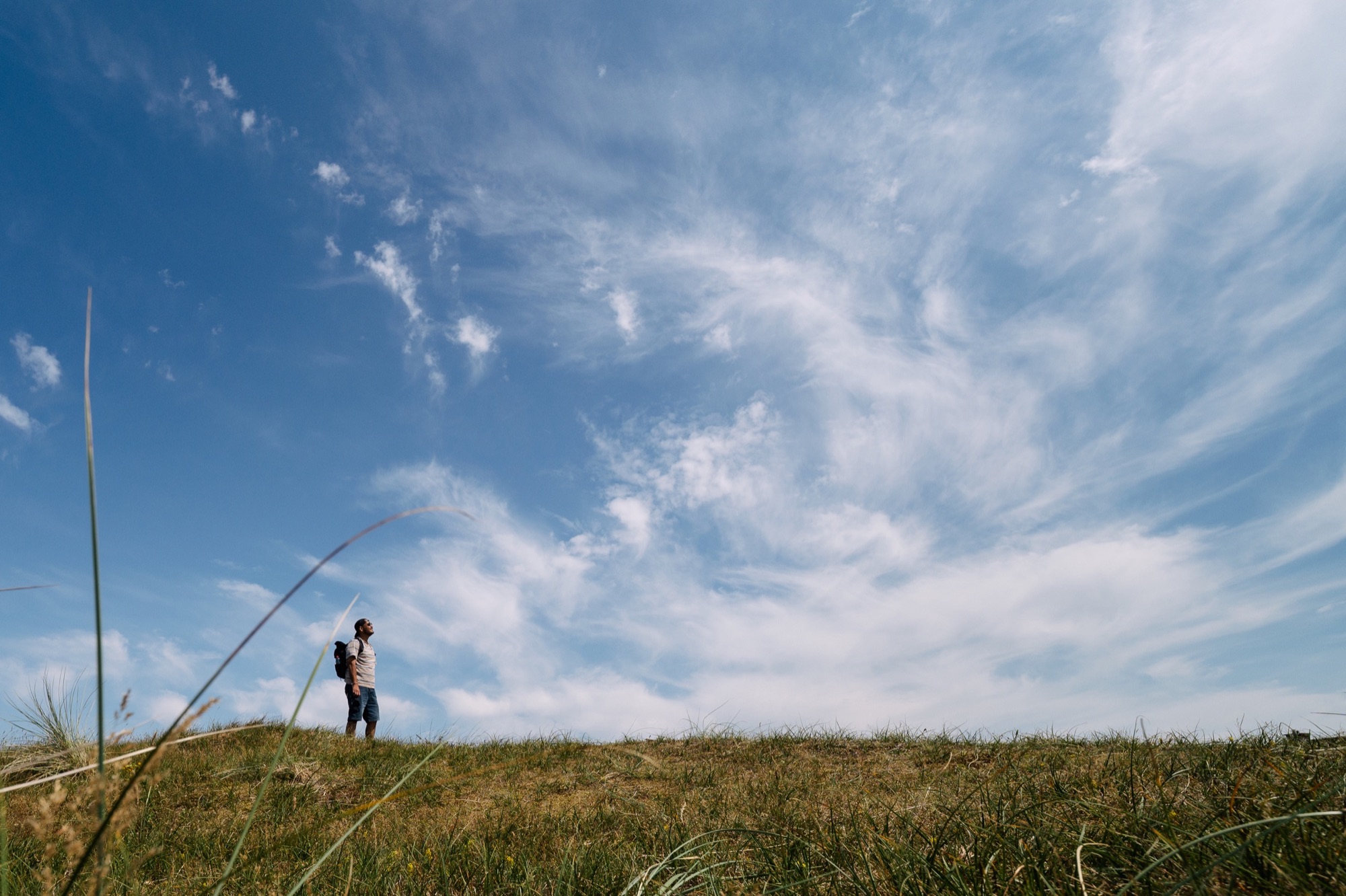 Person walking through dunes beneath a cloud-filled sky
