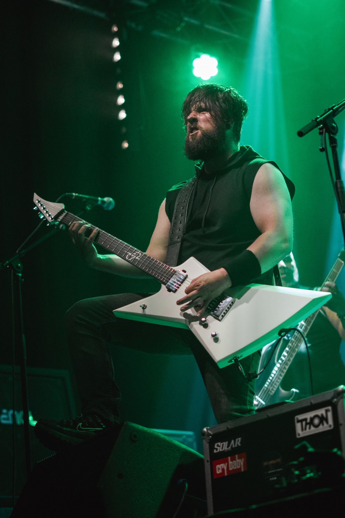 Guitarist performing under green stage lights