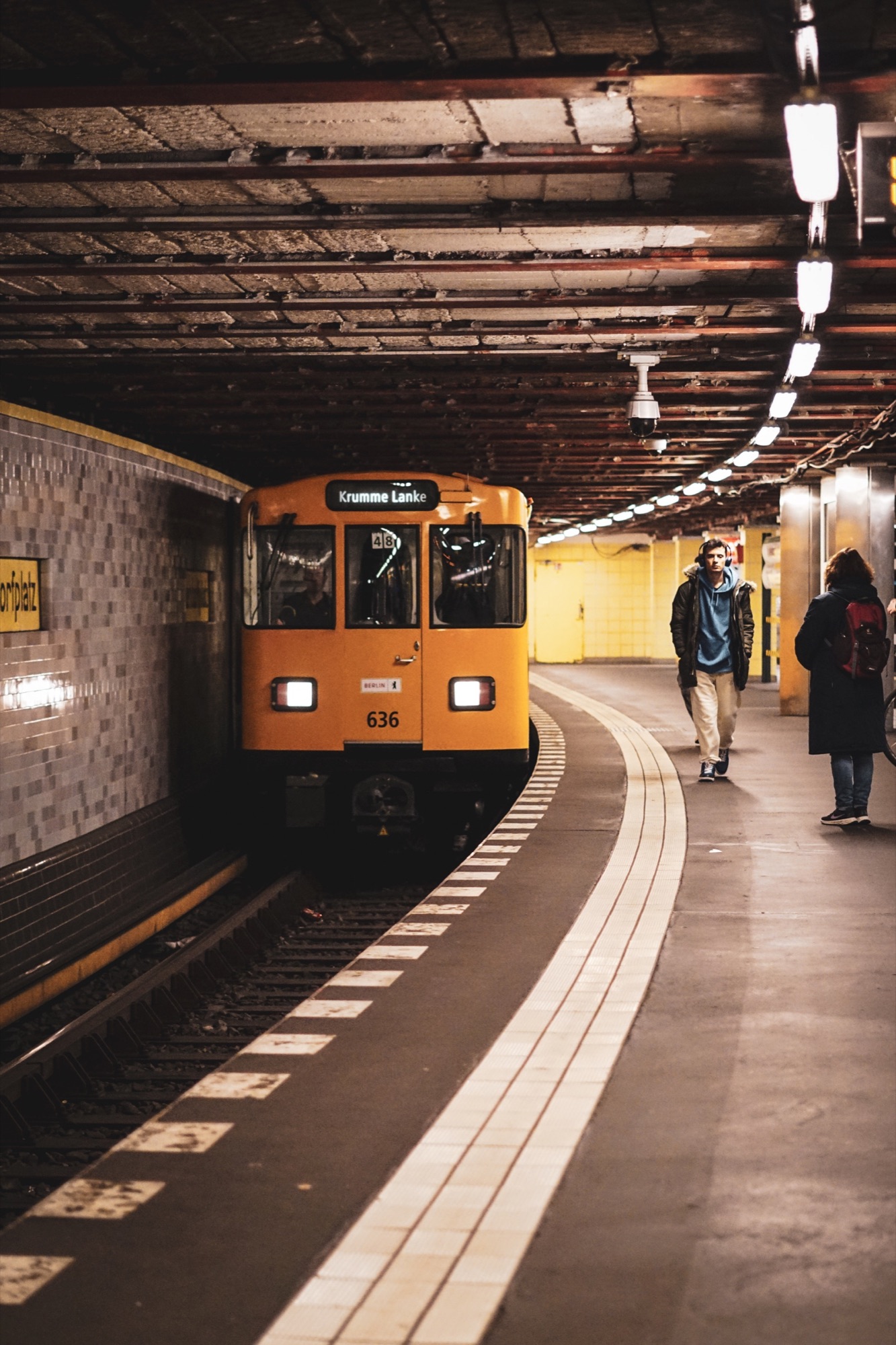 Yellow metro train arriving at a Berlin station